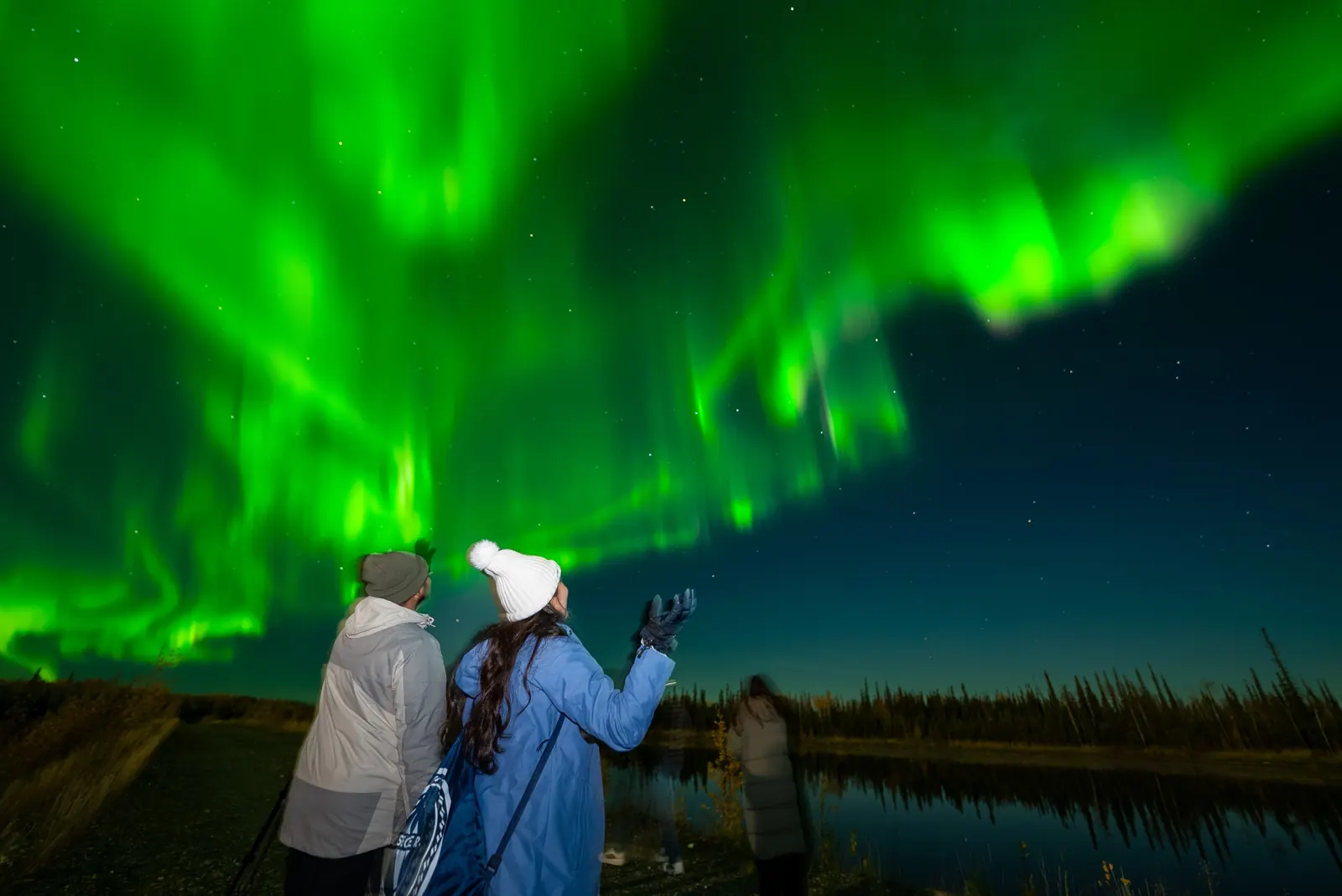 SkyChase guests watch green aurora reflected in a lake, September 23, 2026.